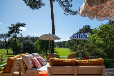 Miniature Location salle Lacanau (Gironde) - La Baignoire #2 Chambre lumineuse avec lit double, balcon donnant sur un espace arboré, rideaux rouges et lampe de chevet allumée.