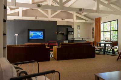 Miniature Location salle Lacanau (Gironde) - La Baignoire #22 Chambre lumineuse avec lit double, balcon donnant sur un espace arboré, rideaux rouges et lampe de chevet allumée.