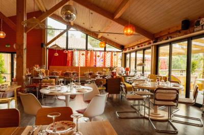 Miniature Location salle Lacanau (Gironde) - La Baignoire #12 Chambre lumineuse avec lit double, balcon donnant sur un espace arboré, rideaux rouges et lampe de chevet allumée.