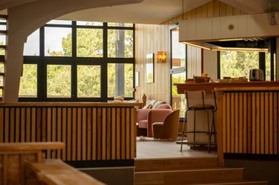 Miniature Location salle Lacanau (Gironde) - La Baignoire #16 Chambre lumineuse avec lit double, balcon donnant sur un espace arboré, rideaux rouges et lampe de chevet allumée.