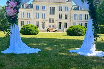 Un groupe de musiciens joue en plein air devant un grand bâtiment de style classique, entouré d'invités en tenue claire.