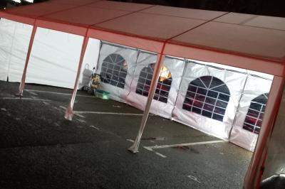 Intérieur d'une tente blanche avec des parois transparentes laissant voir un jardin et une porte en bois.