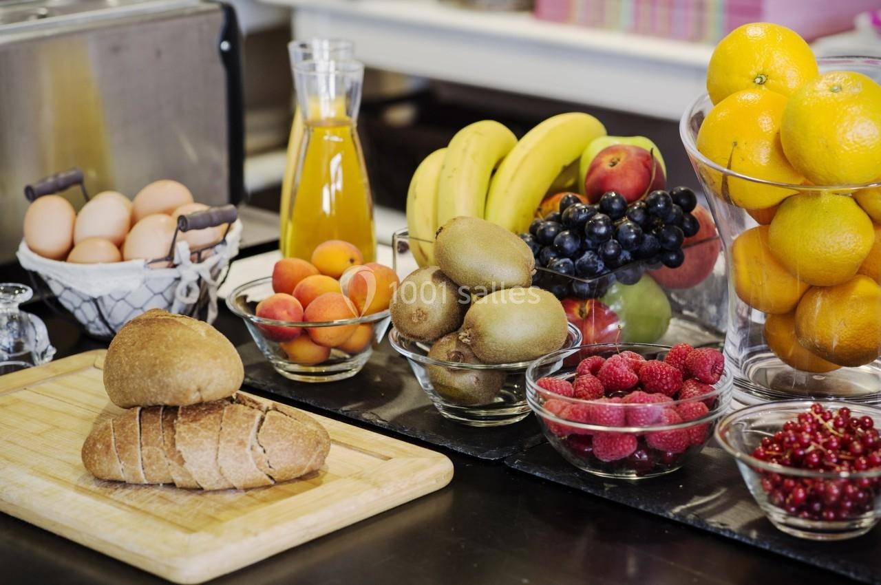 REPAS Assortiment de fruits, pain, œufs et jus d'orange disposés sur une table dans un cadre de cuisine.