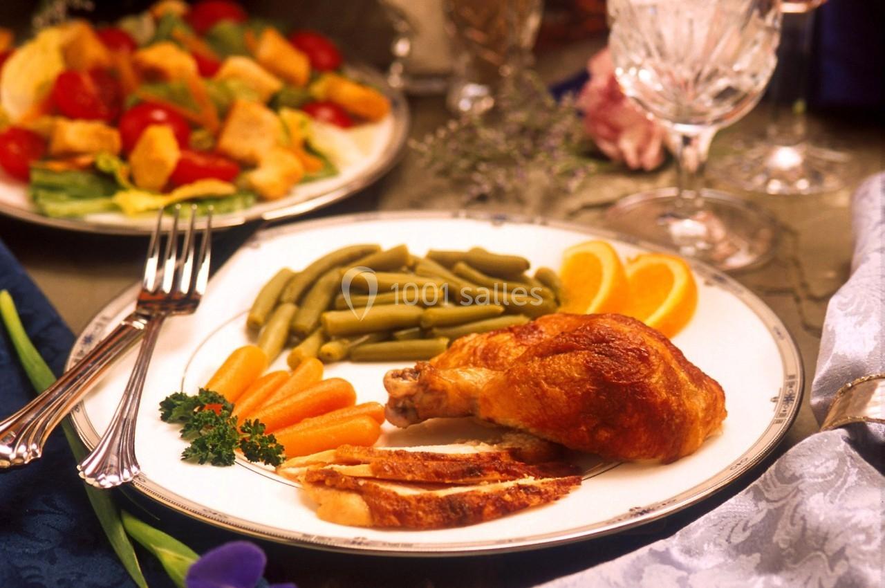 REPAS Assiette garnie de poulet rôti, haricots verts, carottes et tranches d'orange, avec une salade en arrière-plan.