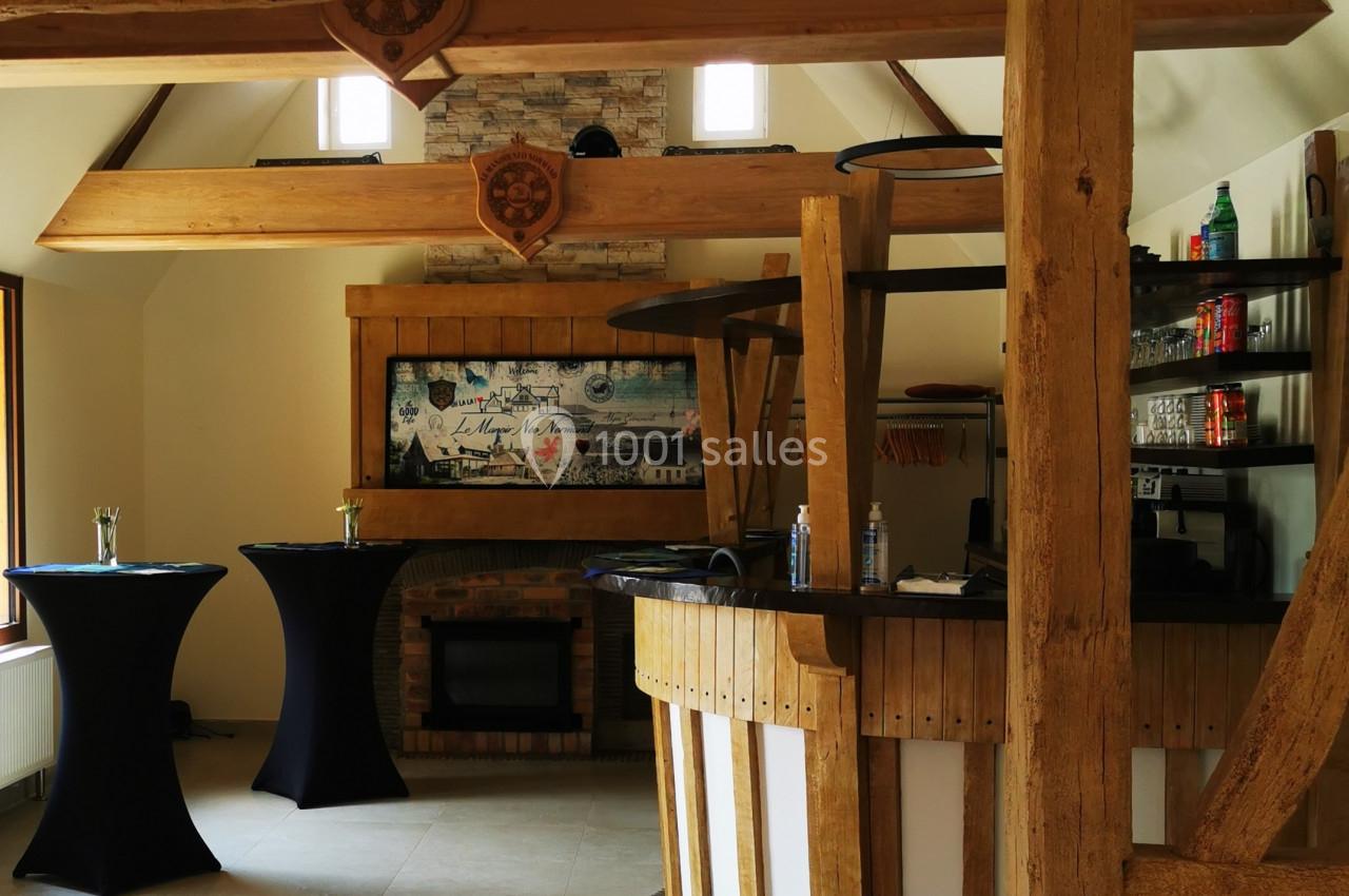 Location salle Saint-Samson-de-la-Roque (Eure) - Manoir Néo Normand #46 Intérieur d'une salle avec poutres apparentes, bar en bois arrondi et tables hautes habillées de nappes noires.