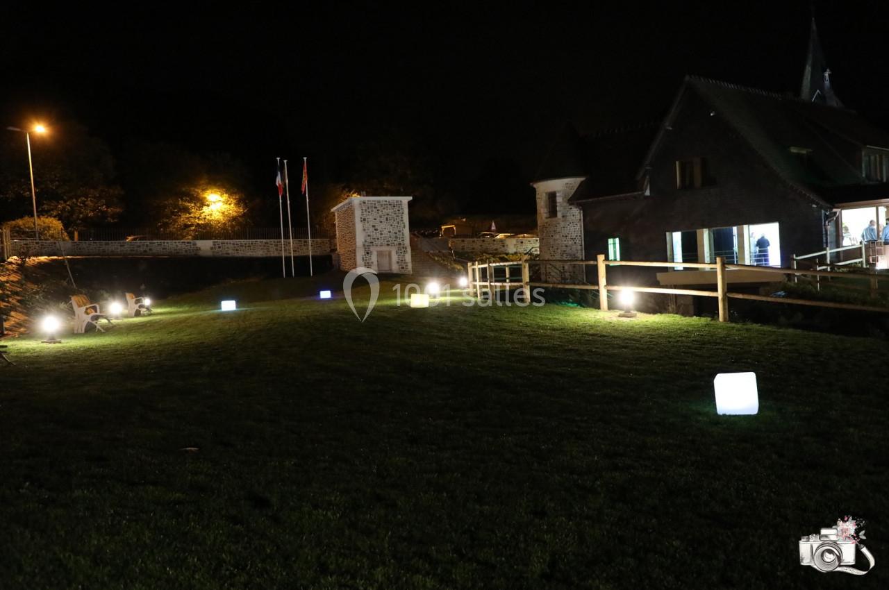 Location salle Saint-Samson-de-la-Roque (Eure) - Manoir Néo Normand #55 Pelouse éclairée par des cubes lumineux colorés, avec un bâtiment en arrière-plan et un pont en bois.