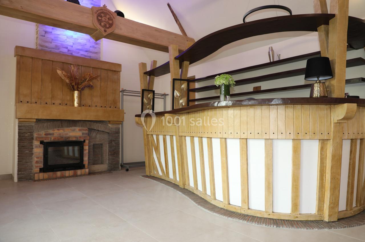 Location salle Saint-Samson-de-la-Roque (Eure) - Manoir Néo Normand #80 Comptoir en bois sculpté avec étagères, situé près d'une cheminée en briques dans un espace intérieur lumineux.