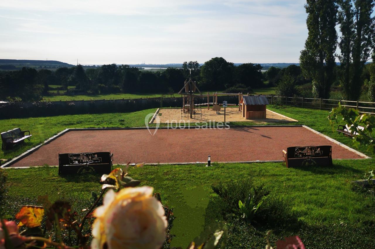 Location salle Saint-Samson-de-la-Roque (Eure) - Manoir Néo Normand #81 Aire de jeux extérieure avec structure en bois, bac à sable, bancs et vue sur un paysage verdoyant en arrière-plan.