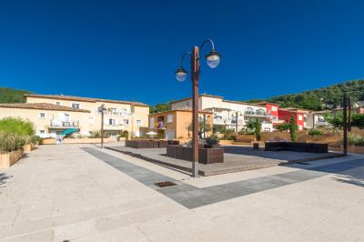 Salon lumineux avec canapé en cuir brun, table basse et accès à un balcon meublé donnant sur un paysage verdoyant.