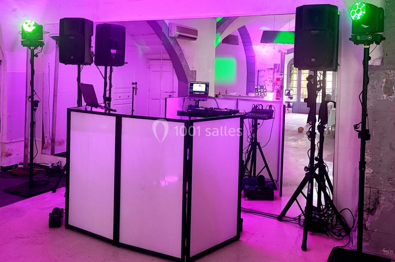 Installation de matériel de sonorisation et d'éclairage avec une table de mixage dans une salle éclairée en rose.