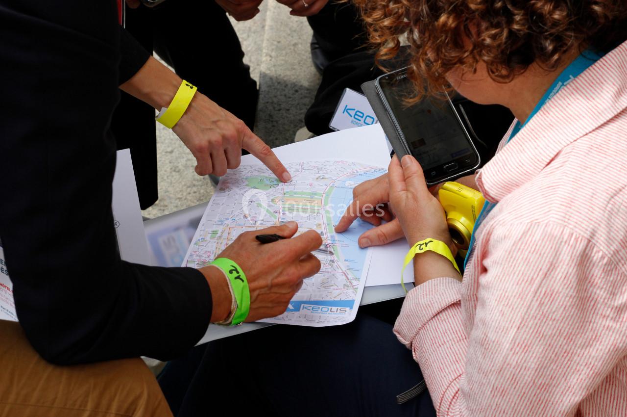Deux personnes consultent une carte imprimée, l'une pointant un lieu précis tandis que l'autre prend des notes.