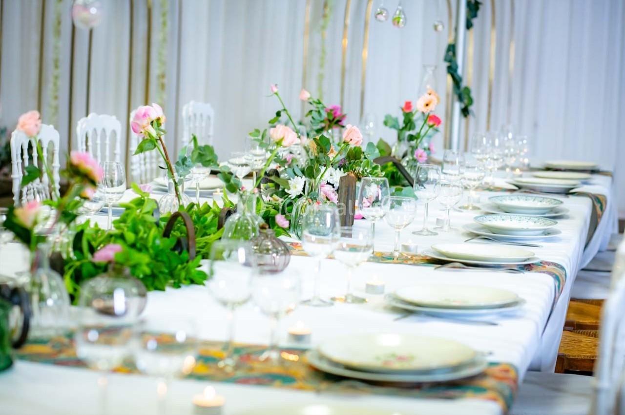 Table décorée avec des fleurs, vaisselle élégante et bougies, prête pour un repas ou un événement festif.