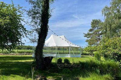 Toilettes sèches en bois clair avec abattant vert, éclairées par une lampe fixée au mur.