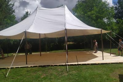Toilettes sèches en bois clair avec abattant vert, éclairées par une lampe fixée au mur.