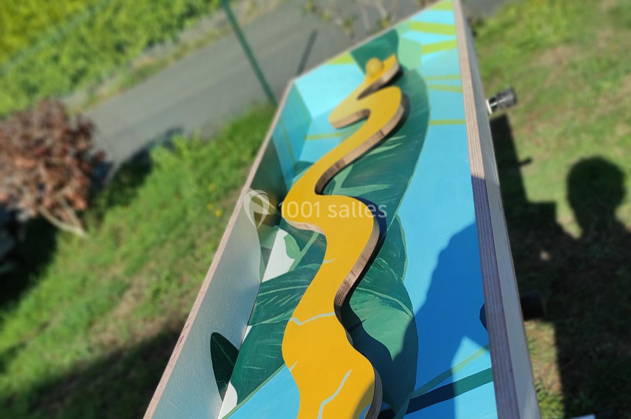 Planche en bois décorée d'une peinture colorée représentant un chemin sinueux sur un fond de paysage tropical.