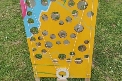 Disque en bois avec des cercles numérotés et des pions en bois disposés sur différentes zones de points.