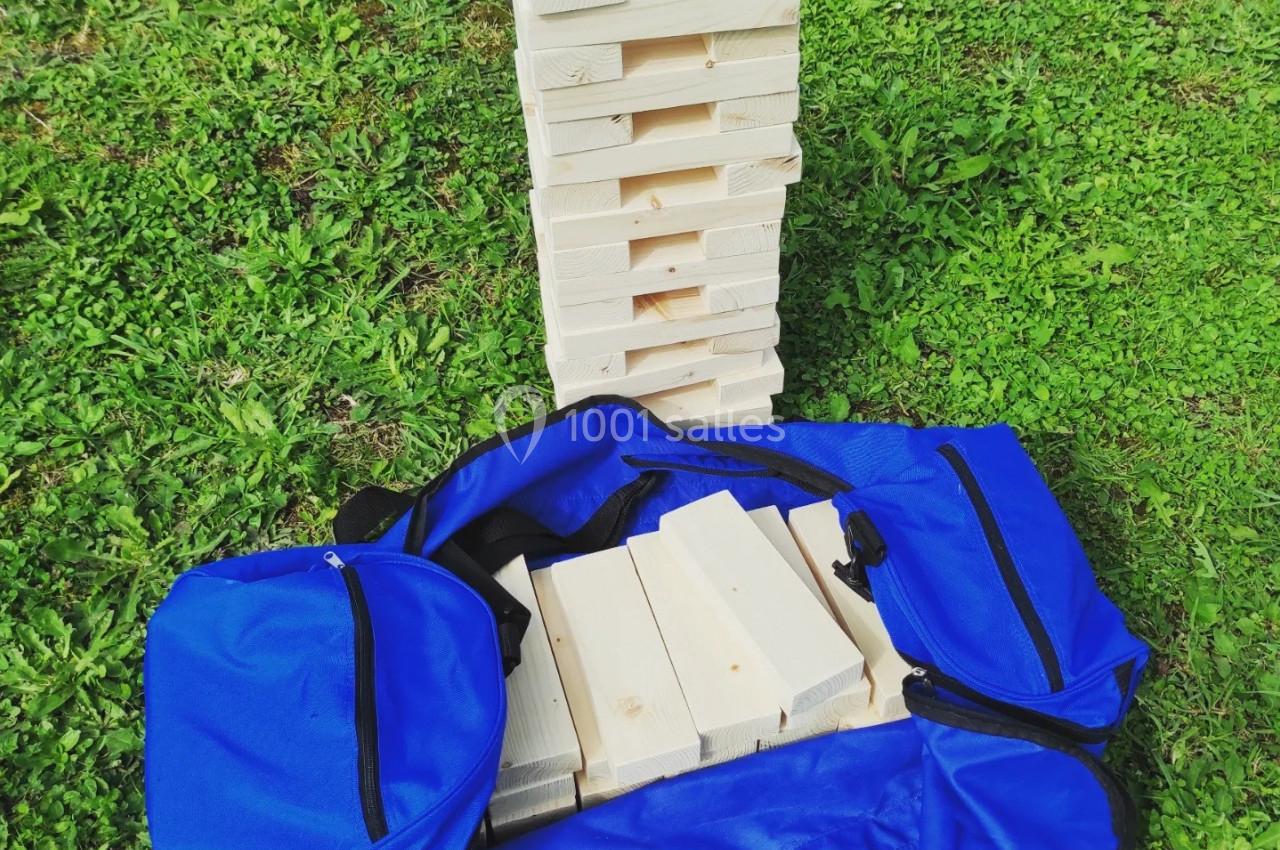 Tour en bois démontable posée sur une pelouse, avec des pièces en bois et un sac de transport bleu ouvert au sol.