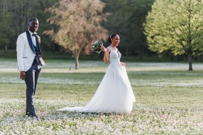 Miniature Bookman Photography #3 Un couple de mariés pose près d'une voiture ancienne blanche devant un bâtiment historique et des arbres.
