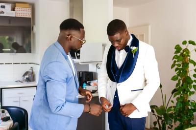 Miniature Bookman Photography #5 Un couple de mariés pose près d'une voiture ancienne blanche devant un bâtiment historique et des arbres.