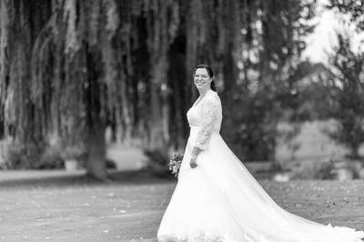 Miniature Bookman Photography #7 Un couple de mariés pose près d'une voiture ancienne blanche devant un bâtiment historique et des arbres.