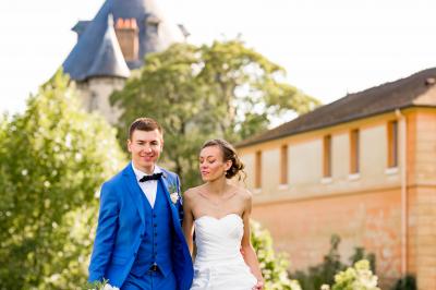 Miniature Bookman Photography #10 Un couple de mariés pose près d'une voiture ancienne blanche devant un bâtiment historique et des arbres.
