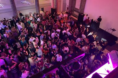 Des serveurs en tenue formelle apportent des plateaux avec des desserts ornés de cierges magiques dans une ambiance festive.