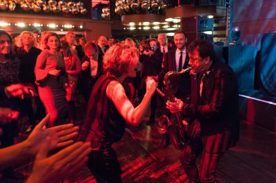 Des serveurs en tenue formelle apportent des plateaux avec des desserts ornés de cierges magiques dans une ambiance festive.