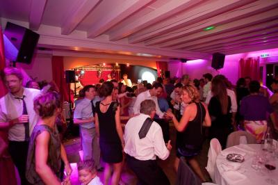 Des serveurs en tenue formelle apportent des plateaux avec des desserts ornés de cierges magiques dans une ambiance festive.