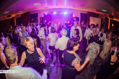 Des serveurs en tenue formelle apportent des plateaux avec des desserts ornés de cierges magiques dans une ambiance festive.