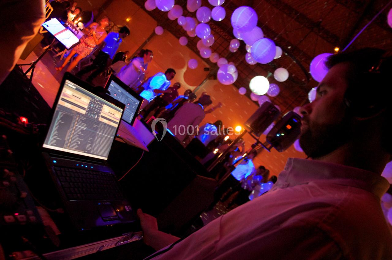 Un DJ utilise un ordinateur portable pour mixer de la musique lors d'un événement avec des lumières et des invités.