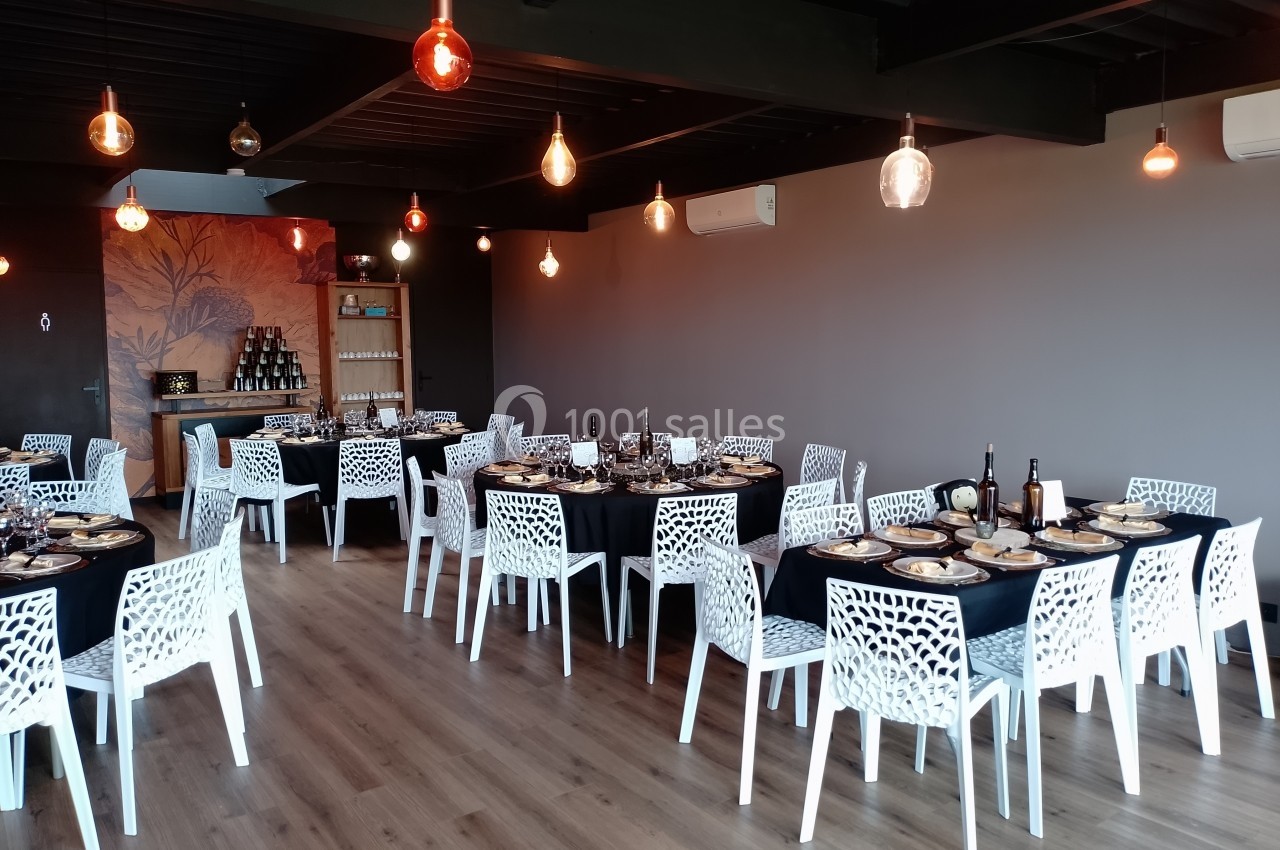 Location salle Saint-Genès-de-Lombaud (Gironde) - Domaine du Château Icla #6 Salle de réception avec tables dressées, chaises blanches ajourées et éclairage suspendu dans un décor moderne.