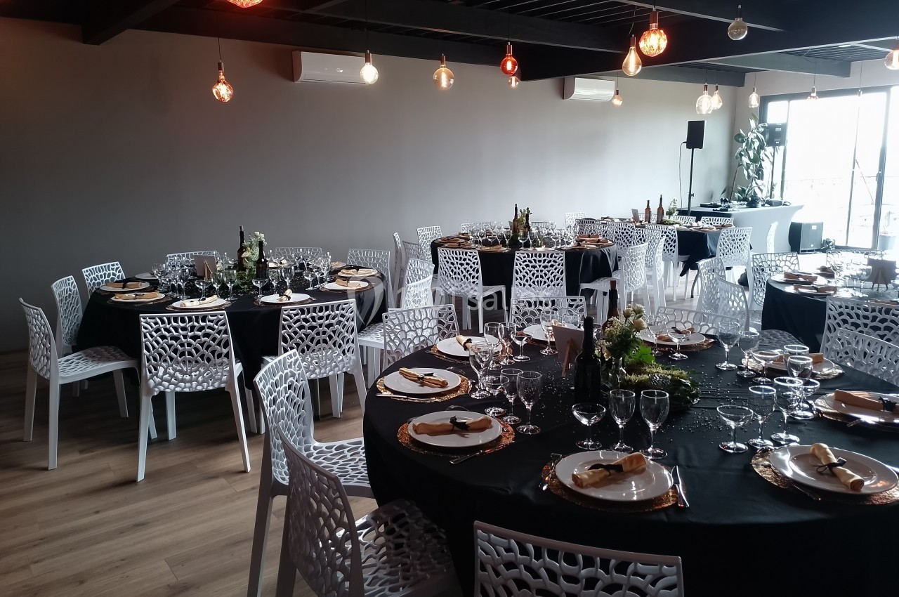 Location salle Saint-Genès-de-Lombaud (Gironde) - Domaine du Château Icla #15 Salle de réception avec tables rondes dressées, nappes noires, chaises blanches ajourées et décorations élégantes.