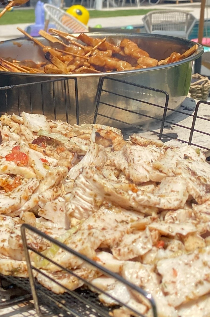 Viande grillée et brochettes en cours de cuisson sur un barbecue en plein air.