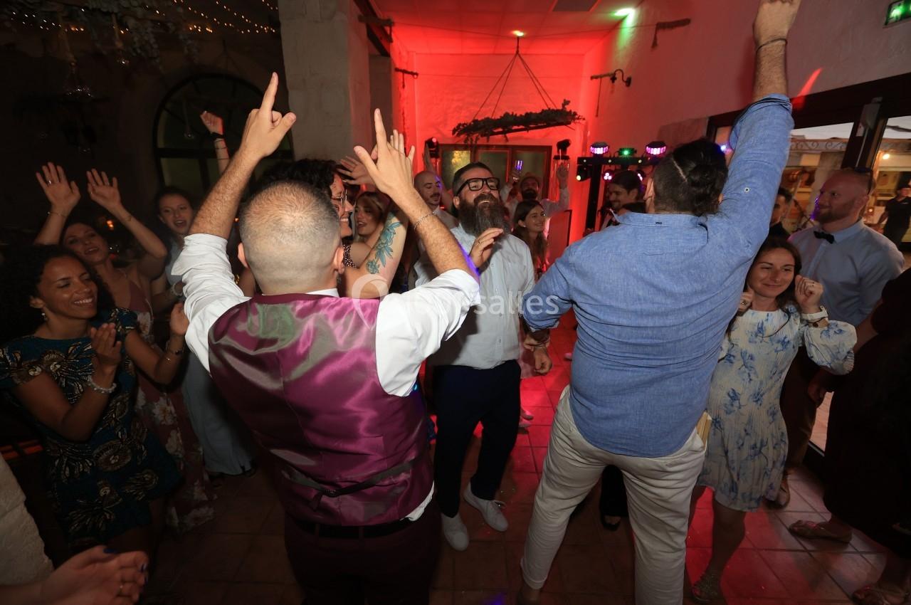 Des personnes dansent et célèbrent dans une salle éclairée de lumières colorées, créant une ambiance festive.