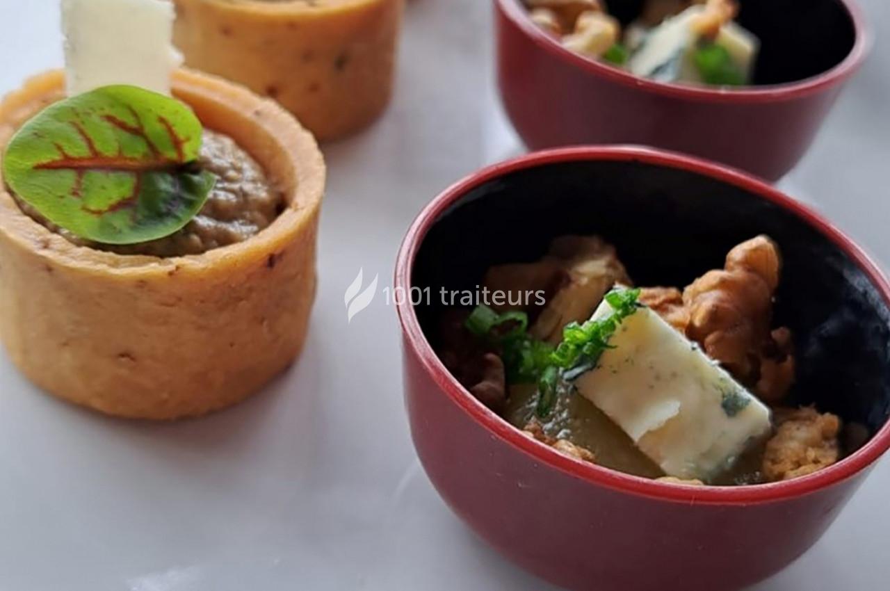 Assortiment de petites bouchées salées, dont des tartelettes et des bols garnis de fromage, noix et herbes fraîches.