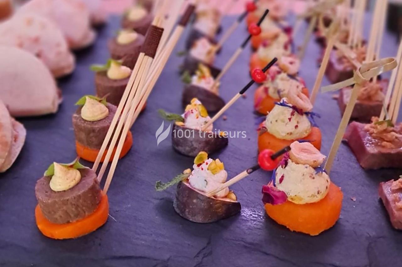 Plateau d'amuse-bouches variés disposés sur une ardoise, avec brochettes et garnitures colorées.