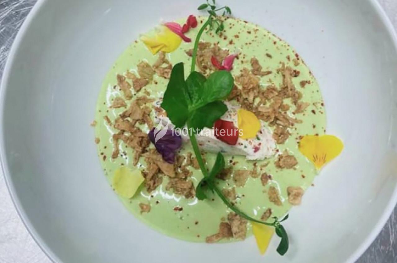 Dessert dressé dans une assiette, avec une mousse verte, des pétales de fleurs colorés et des éclats croustillants.