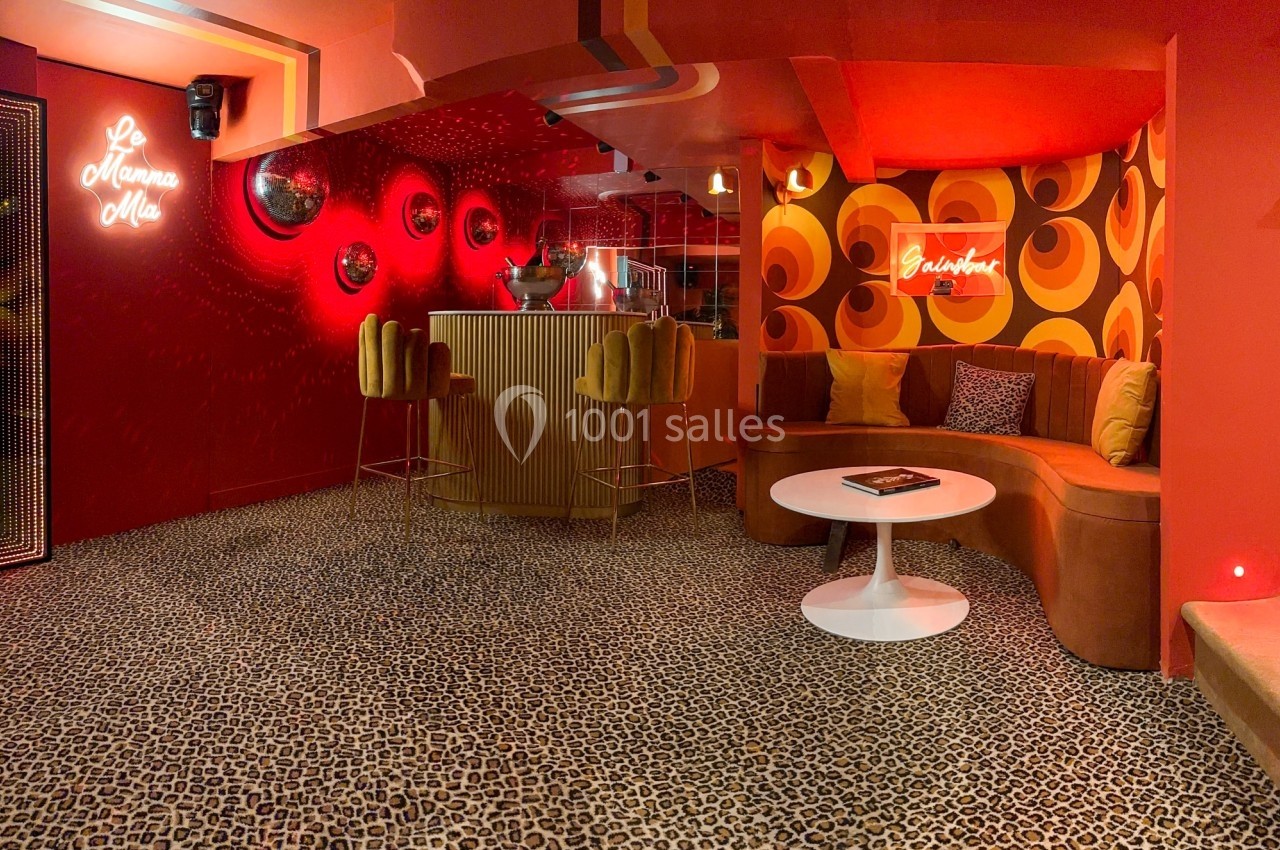 Espace intérieur rétro avec murs rouges, motifs vintage, bar arrondi, tabourets jaunes et canapé en coin.