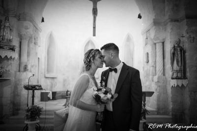 Un couple s'embrasse tendrement dans un cadre naturel entouré de branches d'olivier.