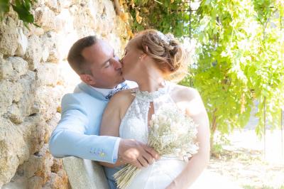 Un couple s'embrasse tendrement dans un cadre naturel entouré de branches d'olivier.