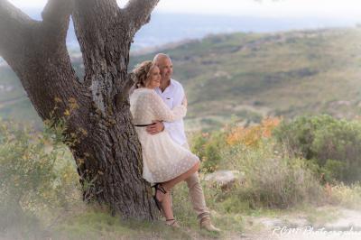 Un couple s'embrasse tendrement dans un cadre naturel entouré de branches d'olivier.