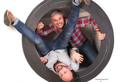 Femme portant des lunettes et un blazer à carreaux, posant devant un fond clair.