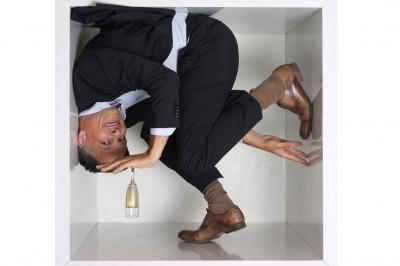 Femme portant des lunettes et un blazer à carreaux, posant devant un fond clair.