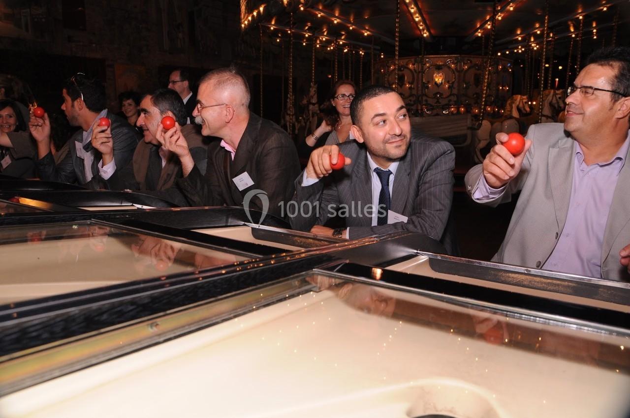 Des personnes assises en groupe tenant des balles rouges dans un cadre festif avec un manège en arrière-plan.