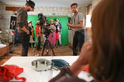 Femme portant des lunettes et un blazer à carreaux, posant devant un fond clair.