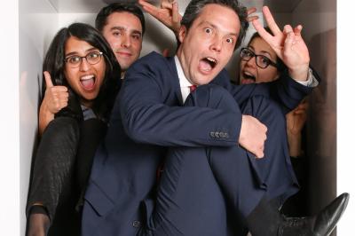 Femme portant des lunettes et un blazer à carreaux, posant devant un fond clair.