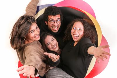 Femme portant des lunettes et un blazer à carreaux, posant devant un fond clair.