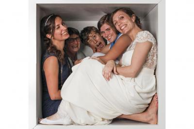 Femme souriante portant un blazer imprimé coloré, un t-shirt gris et un jean, posant devant un fond blanc.