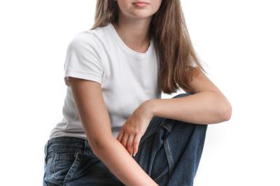 Femme souriante portant un blazer imprimé coloré, un t-shirt gris et un jean, posant devant un fond blanc.