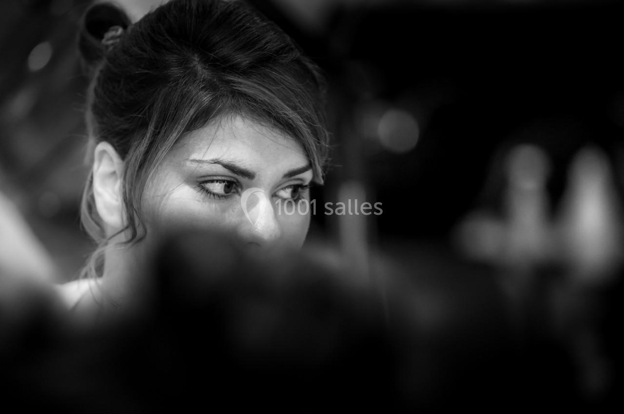 Portrait en noir et blanc d'une femme regardant sur le côté, partiellement masquée par une ombre au premier plan.